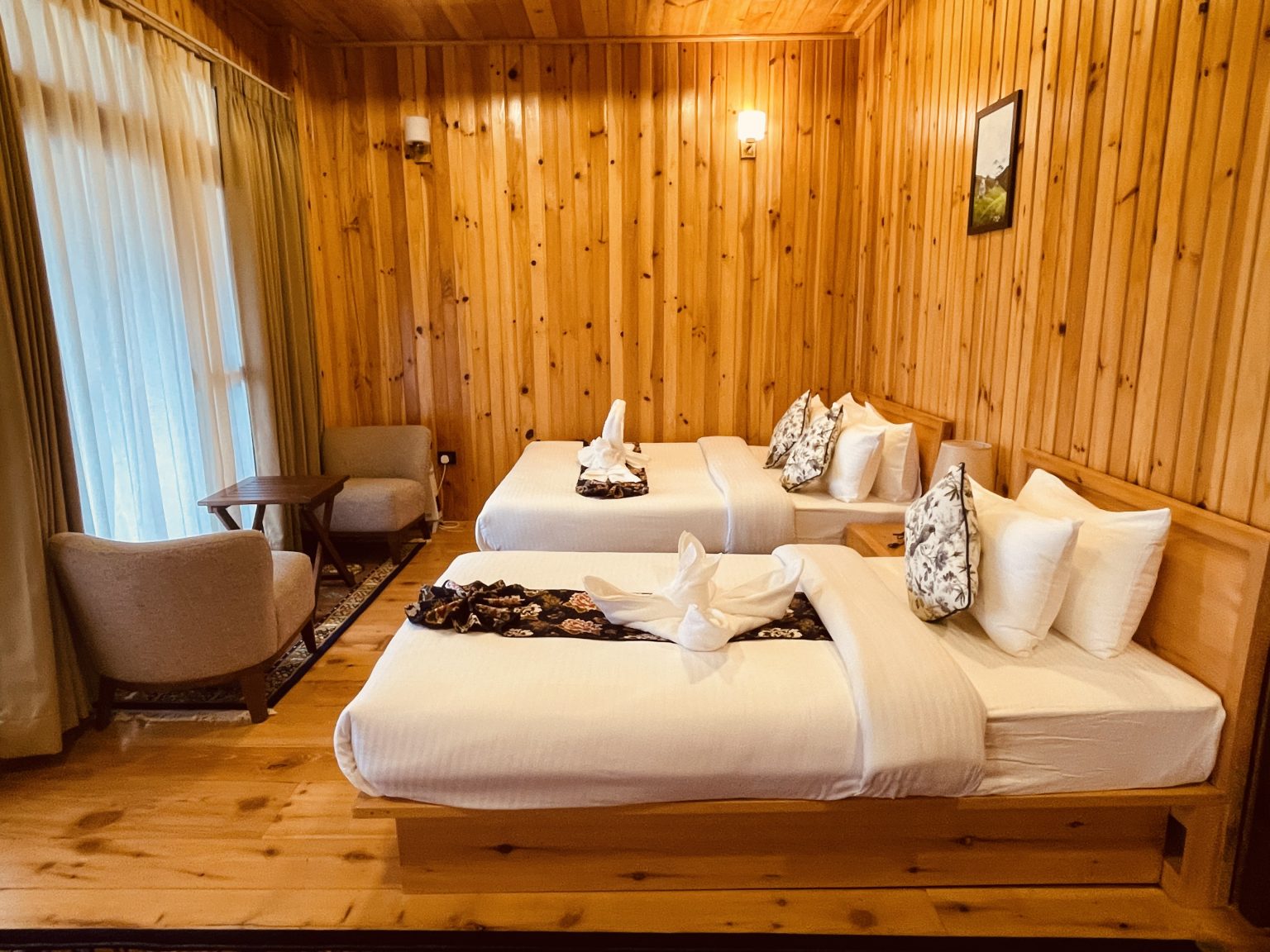 Family Suite at The Happiness Farm with a queen bed, a single bed and a seating corner in a wood-panelled room