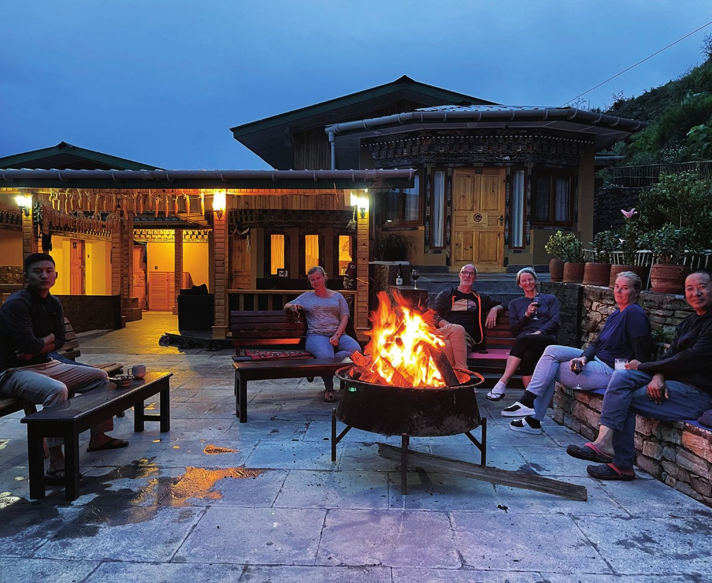 Guests around the bonfire on the stone courtyard at The Happiness Farm in the evening