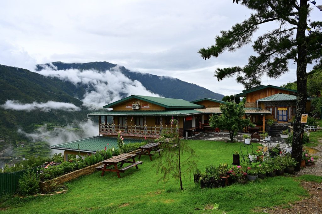 The Happiness Farm guesthouse and lawn with clouds rising from the Paro valley
