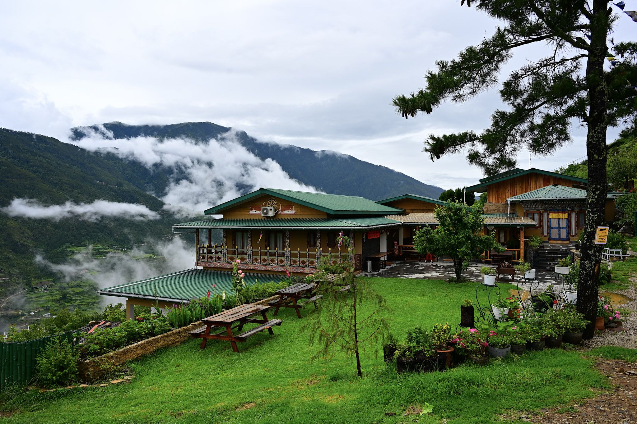 The Happiness Farm guesthouse and lawn with clouds rising from the Paro valley