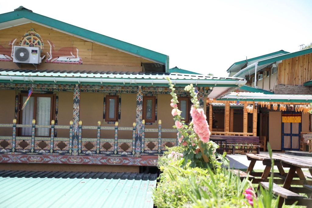 The painted wooden guesthouse at The Happiness Farm with hollyhocks